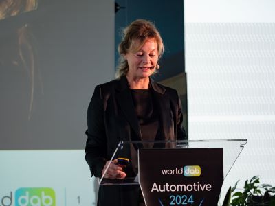 Jacqueline Bierhorst standing behind the lecturn on stage at WorldDAB Automotive 2024